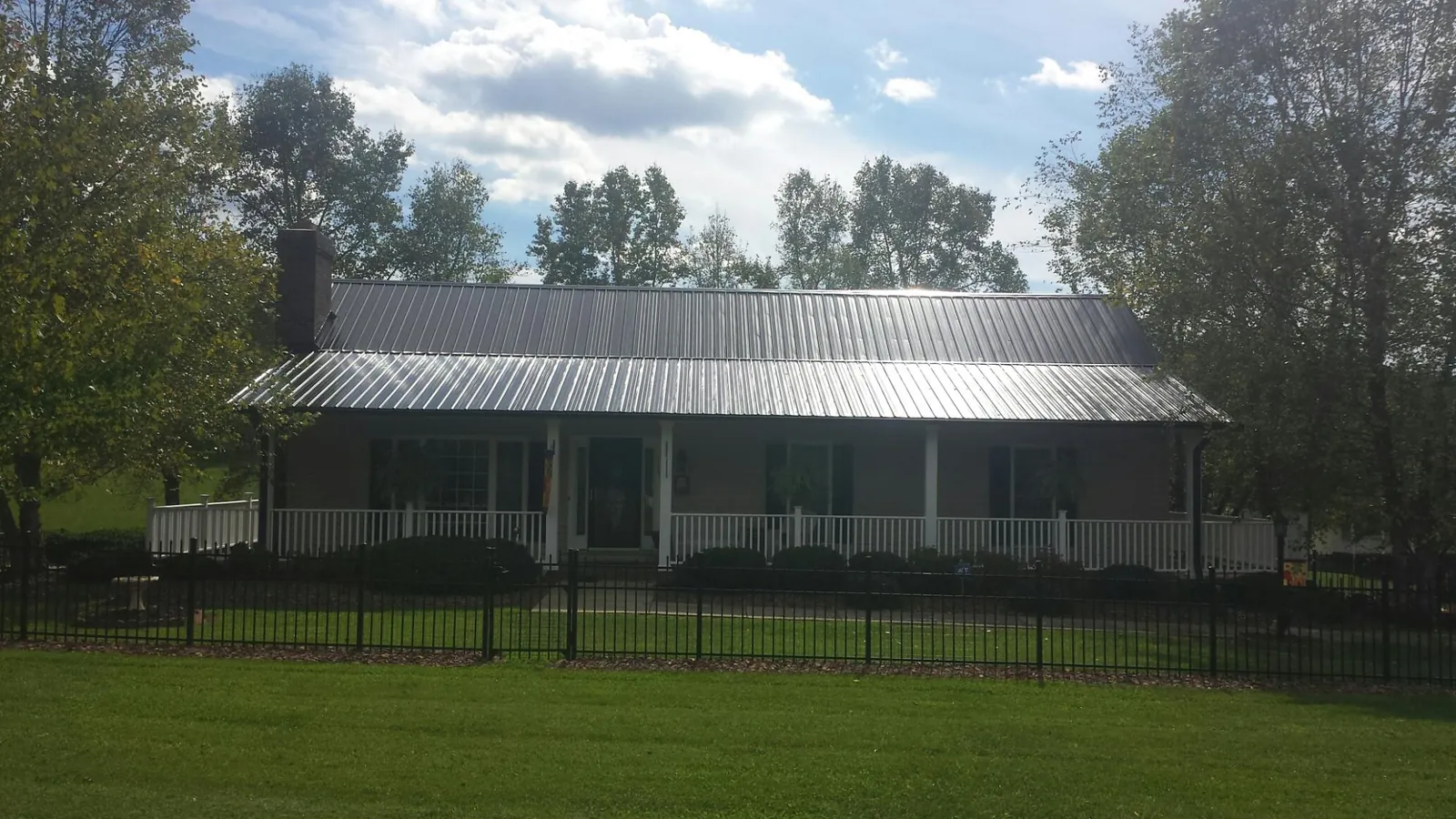 Gray metal roof on a brick ranch with a full width front porch — Gutter Guard Installation work by our crew in Saltese