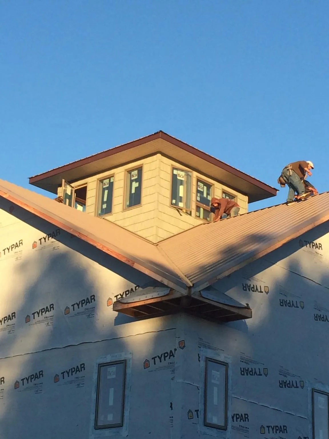 Roofers working around a rooftop cupola on a new metal roof at sunset — Roof Waterproofing in Saltese by Roofing Brothers